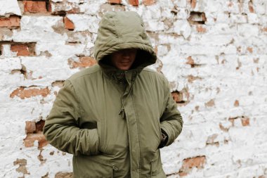 Başında kapüşonlu bir adam, yüzü görünmüyor. Uyuşturucu, hırsızlık ve suç kavramı. Beyaz Retro Grunge Tuğla Duvarlı Kırmızı Arkaplan