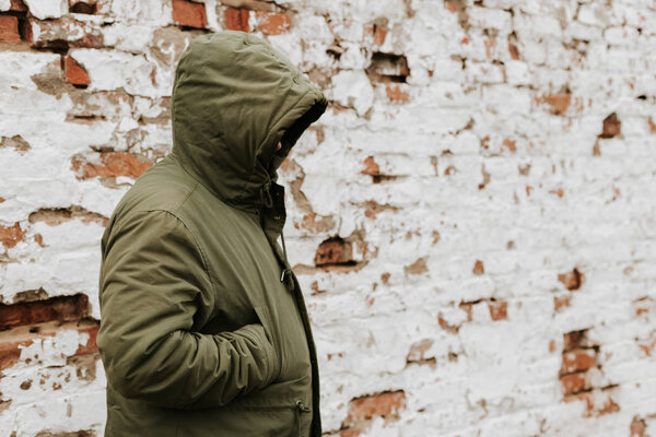 Парень с капюшоном на голове, его лицо не видно. Понятие наркотиков, воровства и преступности. Красный с белым ретро-гримом
