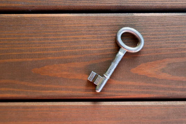 Stříbrný starý klíč na starém dřevěném pozadí, pohled shora. Klíč k novému domovu, koncept nového domu — Stock fotografie