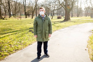 Şehir parkında tıbbi maske takan hasta bir adam. Corona virüsü salgını. Hava kirliliği, zatürree salgını, sis veya salgın hastalık kavramı