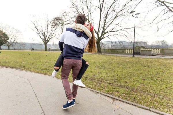 Sevgili sevgilisini kollarına alan mutlu erkek arkadaşınla yakınlaş. Hoş bir çift genç bahar parkında yürüyor..