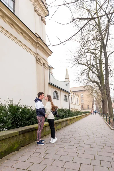 Young couple in love outdoor. Cute couple of young people is walking in spring old town on Weekend Vacation. Happy guy and girl kissing.