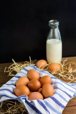 Kahverengi tavuk yumurtaları ve ahşap masada ev sütü şişesi. Çiftlik doğal ürünleri, Paskalya konsepti