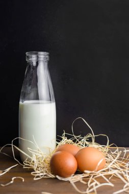 Tahta masada kahverengi tavuk yumurtası ve bir şişe ev sütü. Çiftlik doğal ürünleri, Paskalya konsepti
