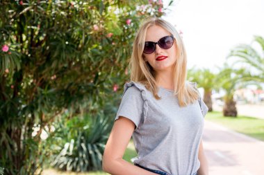 Yaz güneşli bir hayat tarzı. Parkta gezen genç, şık bir hipster kadının portresi.