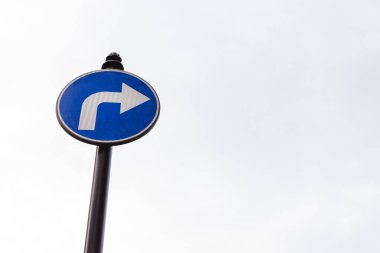 Beyaz bir ok ile mavi yol levhası