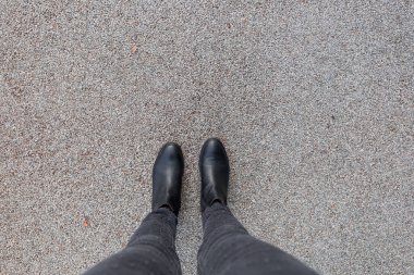 Asfalt beton zeminde duran siyah ayakkabılar. Dışarıda yürüyen ayaklı ayakkabılar. Selphie Modern Hippi