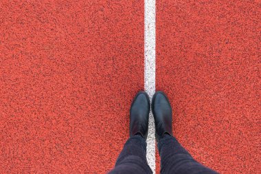 Kırmızı asfalt beton zeminde duran siyah ayakkabılar. Dışarıda yürüyen ayaklı ayakkabılar. Selphie Modern Hippi