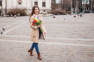 Şehir sokağında bahar laleli güzel bir kadın çiçek buketi. Dışarıda yürüyen mutlu kız. Parkta güzel bir kadının bahar portresi.
