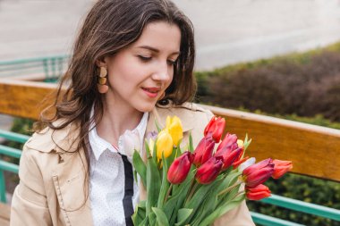 Şehir sokağında bahar laleli güzel bir kadın çiçek buketi. Dışarıda yürüyen mutlu kız. Parkta güzel bir kadının bahar portresi.