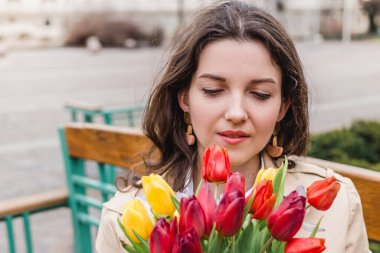 Şehir sokağında bahar laleli güzel bir kadın çiçek buketi. Dışarıda yürüyen mutlu kız. Parkta güzel bir kadının bahar portresi.