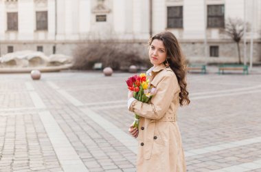 Şehir sokağında bahar laleli güzel bir kadın çiçek buketi. Dışarıda yürüyen mutlu kız. Parkta güzel bir kadının bahar portresi.