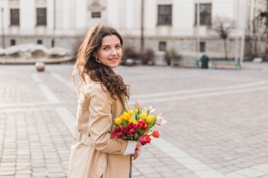 Şehir sokağında bahar laleli güzel bir kadın çiçek buketi. Dışarıda yürüyen mutlu kız. Parkta güzel bir kadının bahar portresi.