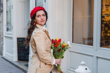 Şehir sokağında bahar laleli güzel bir kadın çiçek buketi. Dışarıda yürüyen mutlu kız. Parkta güzel bir kadının bahar portresi.