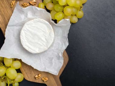 Cevizli tahtanın üzerinde yumuşak peynir ve üzüm.