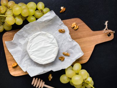 Cevizli tahtanın üzerinde yumuşak peynir ve üzüm.
