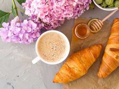 Kahvaltınız kahve, kruvasan, bal kavanozu ve çiçeklerle servis edilir.