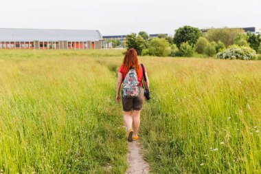Sırt çantalı mutlu genç bir kadın kasabadan çıkıyor. Seyahat ve seyahat tutkusu konsepti.
