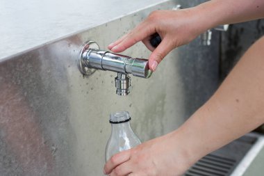 Plastik bir su şişesini musluktan dolduruyorum.
