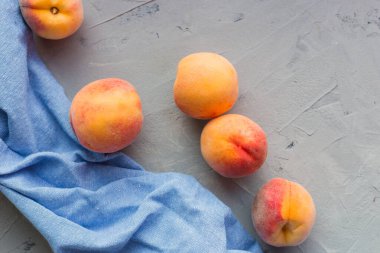 Gri masa zemininde mavi kumaşlı taze şeftaliler. Sonbahar hasat konsepti