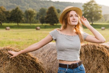 Yazın hasat edilen buğday tarlasında samanlıkta yuvarlanan güzel bir kız. Seçici odak