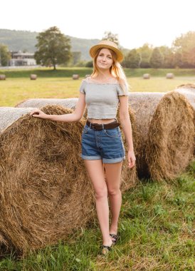 Yazın hasat edilen buğday tarlasında samanlıkta yuvarlanan güzel bir kız. Seçici odak