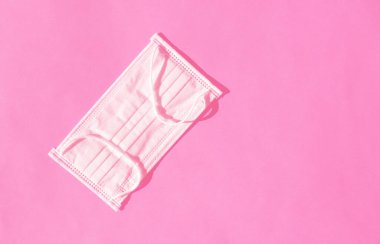 Pembe arka planda cerrahi koruyucu maske. Sağlık sigortası Coronavirus karantinası, hijyen konsepti, pankart için düz uzanma