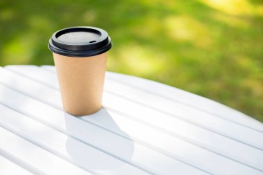 Kahve, çay ya da kokteyl içmek için kahve dükkanından bir kağıt bardak kahve alın ve gidin. Modelleme için, doğa geçmişi. Terasta bir masada iç.
