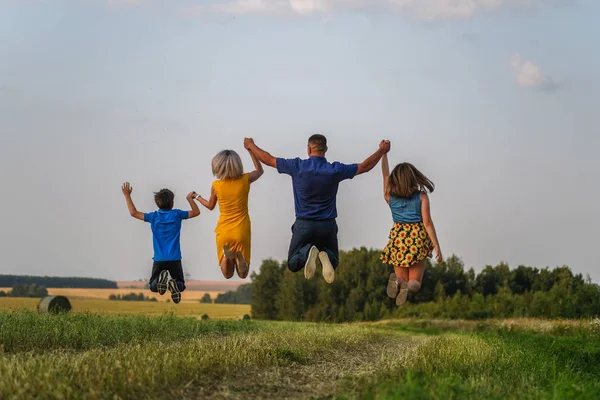 Mom, dad, son and daughter in the high jump holding hands — Stock Photo, Image