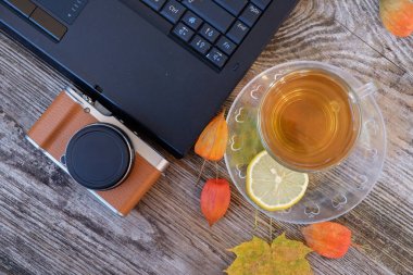 dizüstü bilgisayar, kamera ve masada limonlu yeşil çay bir fincan