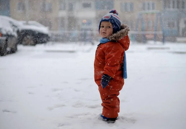 Europeiska pojke stående under snöfallet — Stockfoto