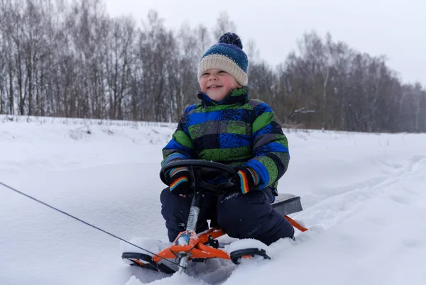 Chłopiec szczęśliwie przejażdżki na sankach w snow zima — Zdjęcie stockowe