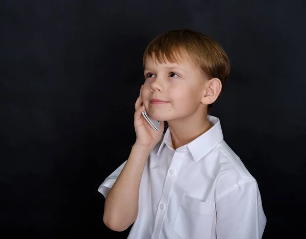 Menino bonito com um sorriso falando ao telefone — Fotografia de Stock