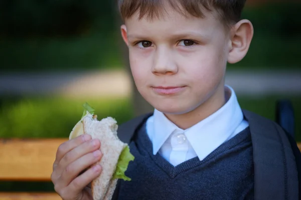 Menino europeu come escola Café da manhã no banco do parque — Fotografia de Stock