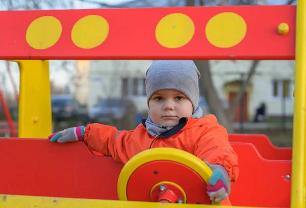 Słodkie mały chłopiec siedzi za kierownicą a dziecko samochód w plac zabaw — Zdjęcie stockowe