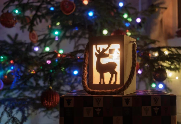 Schöner hölzerner Kerzenständer mit Hirsch und Vintage-Lampe unter dem Weihnachtsbaum. Elemente der Weihnachtsdekoration — Stockfoto