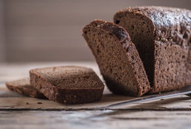 Dikdörtgen çavdar ekmeği ve ahşap bir masada kişniş. Ekmek dilimleme