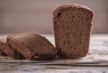 Dikdörtgen çavdar ekmeği ve ahşap bir masada kişniş. Ekmek dilimleme