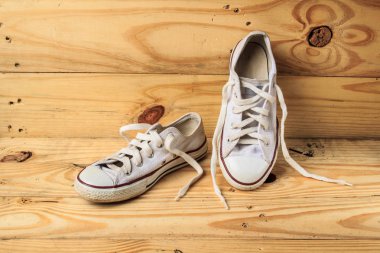 Ahşap zemin üzerinde beyaz spor ayakkabı.