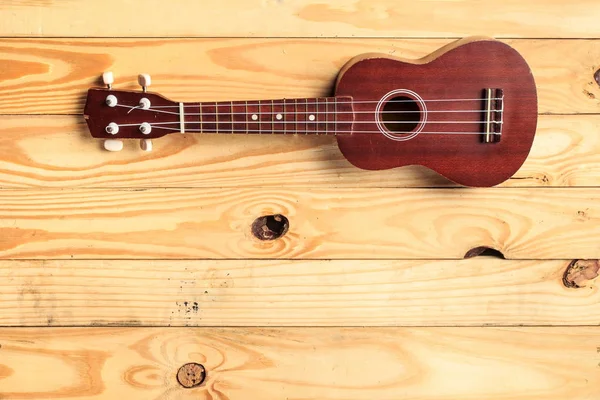 Brązowy ukulele opiera się na drewnianą podłogę — Zdjęcie stockowe