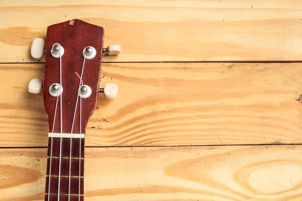 Brown ukulele rests on a wooden floor — Stock Photo, Image