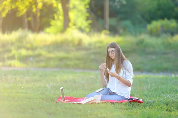 gülümseyen ve onun laptop müzik çalışma parkta oturan genç kız