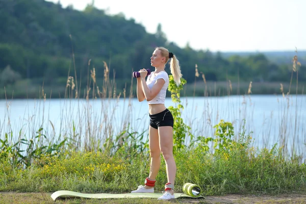 Atleta feminino braço ponderado pernas outdors treino — Fotografia de Stock