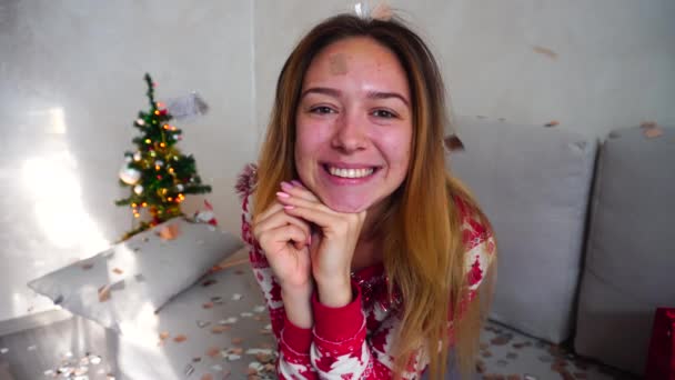 Menina Retrato Sorriso Olhar para Câmera Árvore de Natal Bokeh Xmas Eva Luzes Ano Novo Confetti em casa — Vídeo de Stock