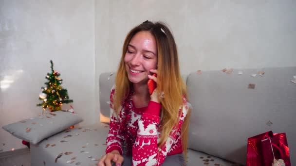 Giovane ragazza Ritratto Sorriso Talk su Smart Phone sull'albero di Natale Bokeh Vigilia di Natale Luci di Capodanno Confetti sfondo a casa — Video Stock
