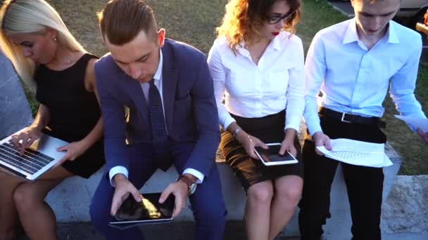 Equipe de negócios Sentado perto do escritório do centro com documentos, laptop, tecnologia de tablet contra o sol — Vídeo de Stock