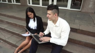 Kadın ve beyaz erkek kullanım belgeleri, dizüstü basın klavye ofis binası merdivenlerde otur genç güzel iş kadını