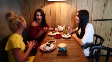 Üç güzel kadın gülümseme Cafe içinde konuşma, sırları, söyle yemek, kahve iç.