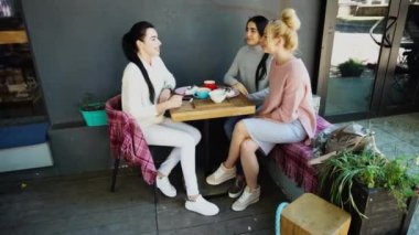 Üç güzel kadın gülümseme Cafe içinde konuşma, sırları, söyle yemek, kahve iç.