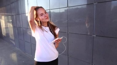 Öğrenci kız dinle müzik için kulaklık üzerine koyar unravels